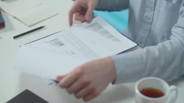 Az irodai dolgozó megvizsgálja a dokumentumokat és a grafikákat — Stock videók
