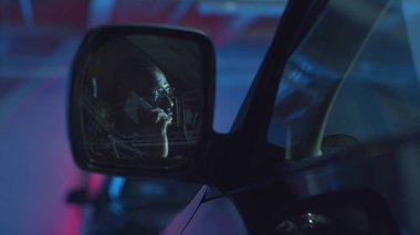 Telefonda konuşan bir adam var. Araba yan aynası. 