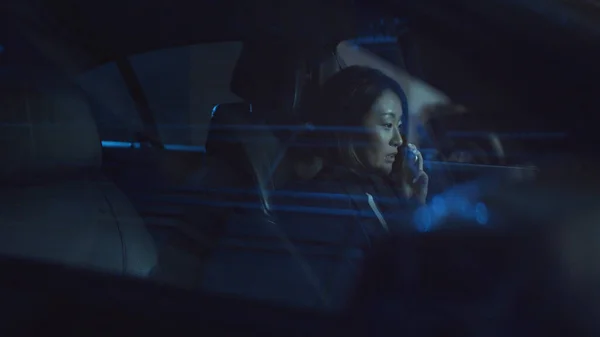 Une femme s'assoit dans une voiture la nuit et parle au téléphone — Photo