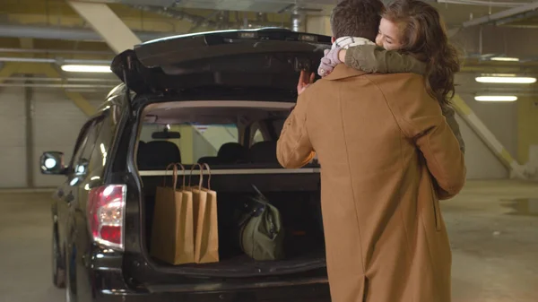 Babası kollarında kızıyla bir arabanın bagajını açtı.