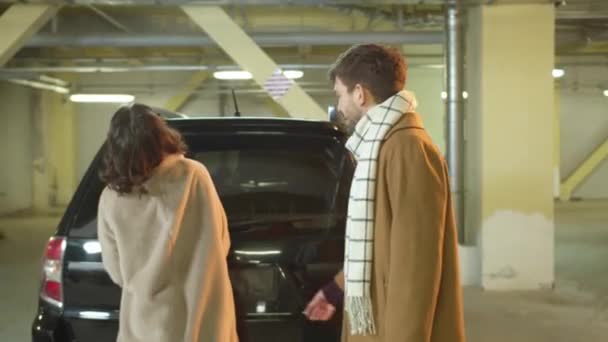 El tipo ayuda a una mujer a abrir el maletero de un coche. — Vídeos de Stock