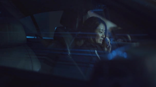 Uma mulher senta-se em um carro à noite e fala ao telefone — Vídeo de Stock