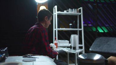 Kadın dövme ustası seans için aletler yapıyor.