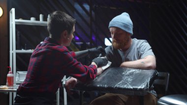 Dövmeci, antiseptik kullanan bir adamın elini ovuşturuyor.