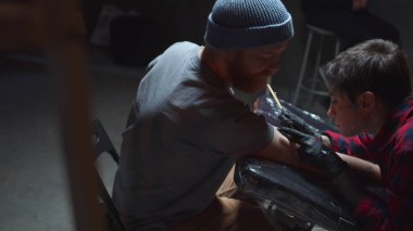 Dövme ustası bir erkek için dövme yapar. Orta boy.