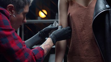 Kız müşterinin koluna geçici dövme yaptırıyor.