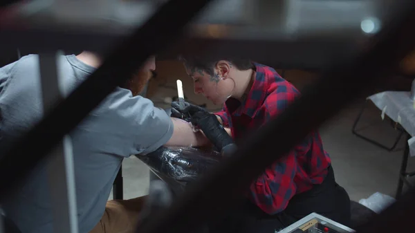 Tattoo master stuffs a tattoo on a arm of a man. Background — Stock Photo, Image