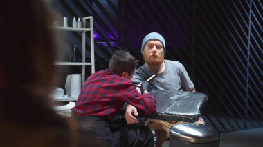 Bir kız dövme yaptıran bir adamı izliyor. Arkaplan