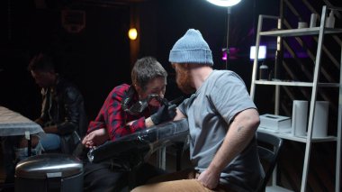 Dövme salonu. Bir kadın dövme üzerinde çalışıyor.