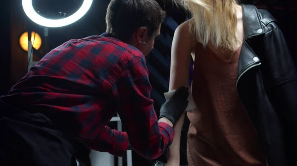 Tattoo umělec utírá ruku ženy s ubrouskem — Stock fotografie