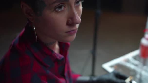 Dziewczyna z kolczykiem przygotowuje igłę do tatuażu — Wideo stockowe
