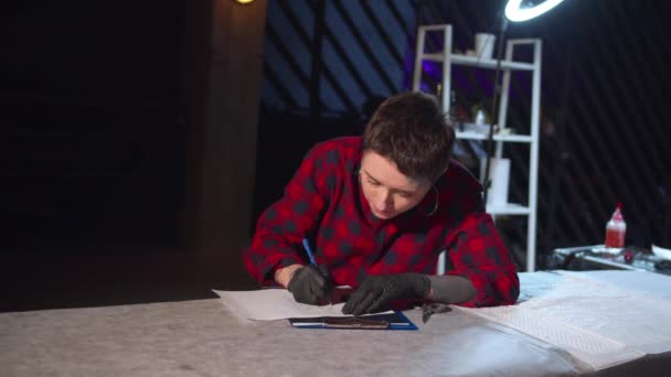 Майстер татуювання малює ескіз на столі — стокове відео