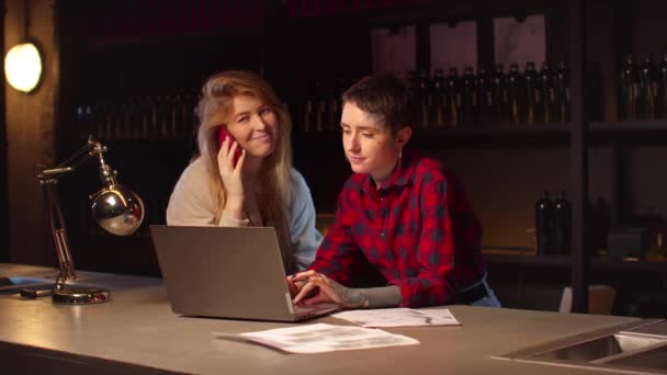 Женщина работает на ноутбуке, другая разговаривает по телефону — стоковое видео