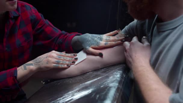 Ένα κορίτσι βάζει ένα προστατευτικό στρώμα σε ένα τατουάζ. Κλείσε. — Αρχείο Βίντεο