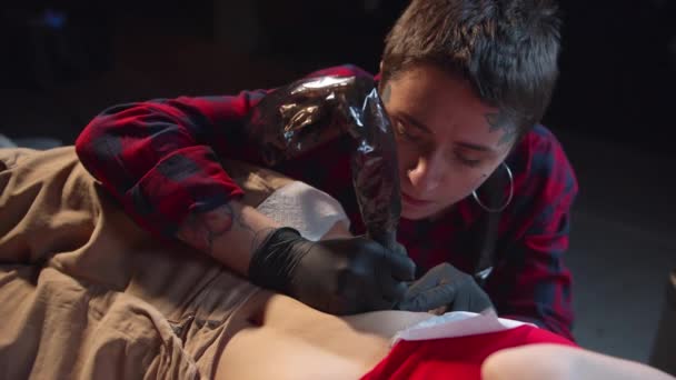 Le maître du tatouage met un tatouage sur le ventre. Gros plan — Video