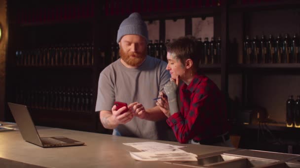 Homme montre des croquis de tatouage sur un téléphone à un tatoueur — Video