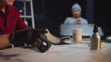 Dövme ustası bir bant ile bir dövme makinesinin hortumunu emniyete alıyor.