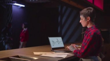 Kadın dizüstü bilgisayar kullanıyor ve kağıda resim çiziyor. Orta boy.