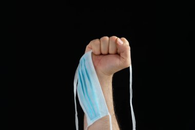 Siyah arka planda Coronavirus 'a karşı mücadele sembolü olarak bir maske kaldırma.
