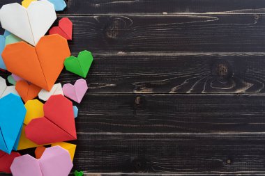 Origami kalpleri farklı renkte ve boyutlarda eskimiş siyah ahşap arka planda.