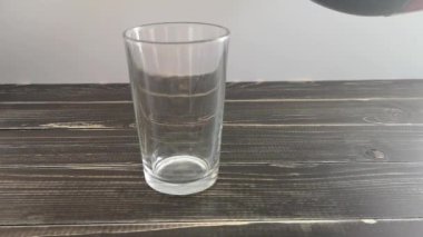 Ahşap bir taklada cam bardak kola ile doluyor.
