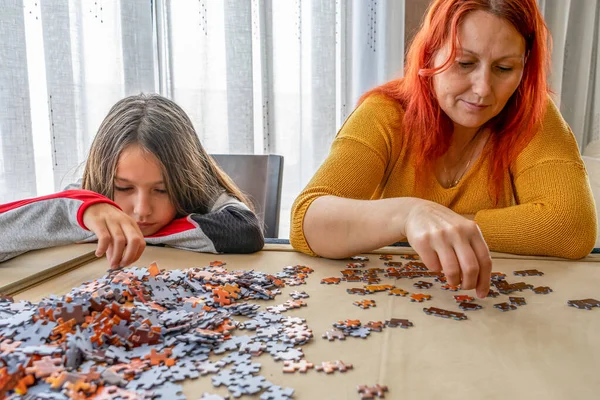 Mother and daughter doing puzzle in the living room at home. Fun concept