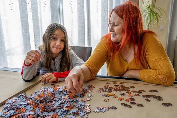 Mother and daughter doing puzzle in the living room at home. Fun concept