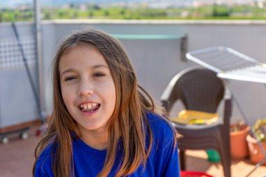 Güneşli bir günde mavi gömlekli güzel bir kız evinin terasında.
