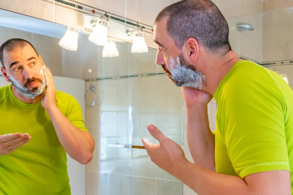 身穿开心果绿衬衫 在镜子前刮胡子的男人 — 图库照片