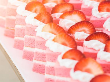 Uluslararası açık büfe restoranının üstünde vanilyalı krema ve taze çilek parçalarıyla dolu yakın plan pembe çilekli kekler..