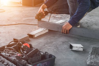 Erkek inşaat işçisi inşaat alanında demir parmaklıkları keskin kıvılcımlarla kesmek için elektrikli açı öğütücü kullanıyor. Boşluk duvar kağıdını kopyala.