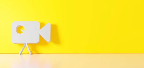 3D рендеринг белого символа иконки видеокамеры, опирающейся на цветную стену с отражением пола с пустым пространством справа — стоковое фото