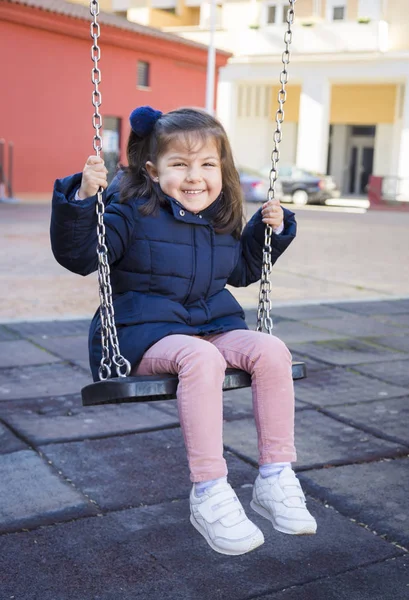 Happy Child girl Laughing and Swinging on a swing at the park Stock Photo