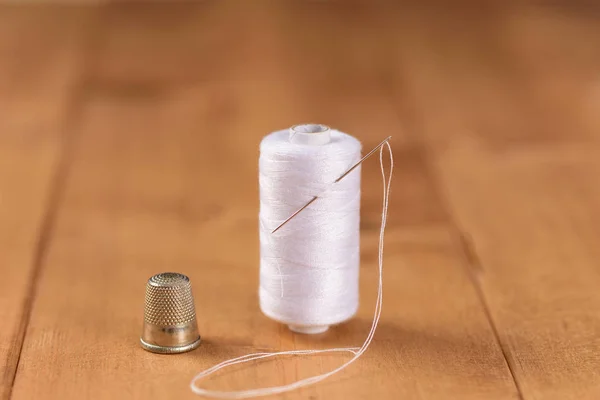 White cotton thread bobbin with needle close up