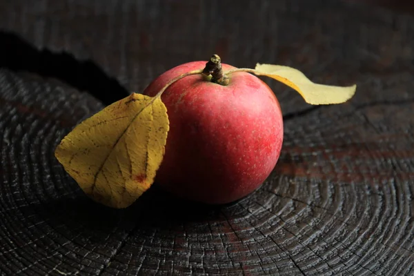 Red apple with leaves on a wooden table. An apple grown in its garden. Natural apple ripped from a branch in the garden.