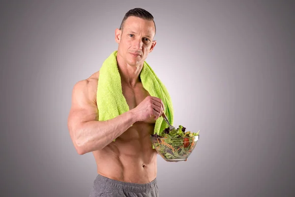 М'язистий чоловік тримає салат — стокове фото