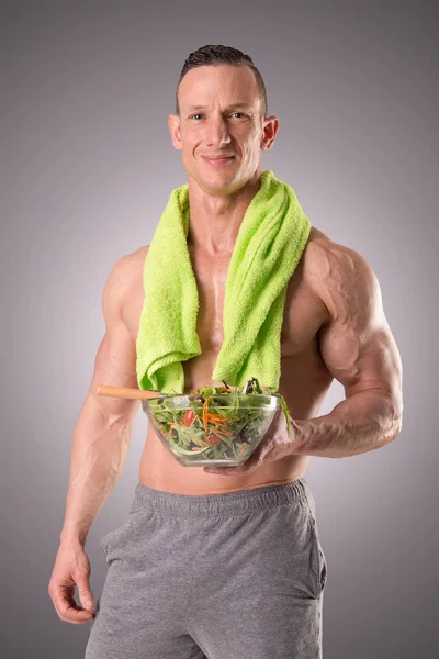 Homem muscular segurando salada — Fotografia de Stock