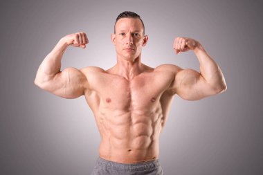 gri bir arka plan üzerinde poz uygun kaslı adam izole