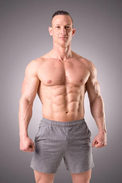 회색 배경에 맞는 근육 남자 포즈 절연 — 스톡 사진