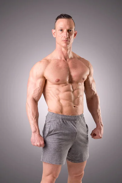 Ajuste muscular hombre posando aislado sobre un fondo gris — Foto de Stock