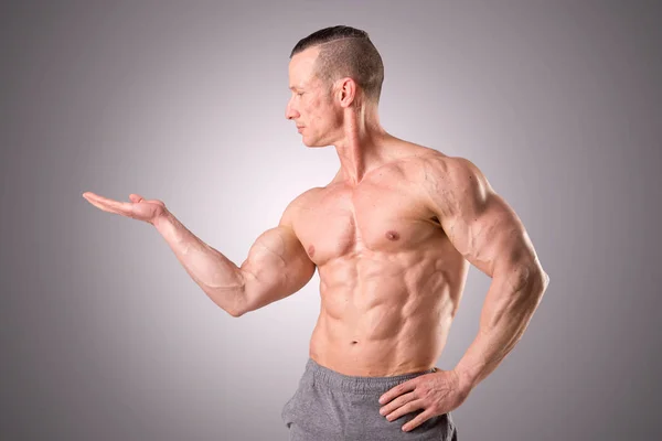 Fit uomo muscoloso posa isolato su uno sfondo grigio — Foto Stock