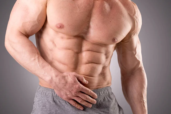 Ajuste muscular hombre posando aislado sobre un fondo gris —  Fotos de Stock