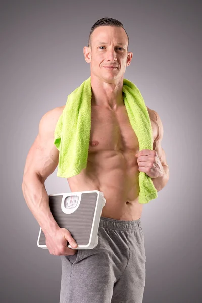 Fit uomo muscoloso posa isolato su uno sfondo grigio — Foto Stock