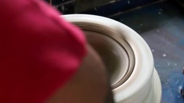 Bir çömlekçinin elleri, son aşamada iki eli olan seramik cilalama işlemini kullanarak bir kase yaratıyor. Fırına girmeden önce