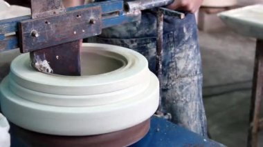 Bir çömlekçinin elleri, son aşamada iki eli olan seramik cilalama işlemini kullanarak bir kase yaratıyor. Fırına girmeden önce