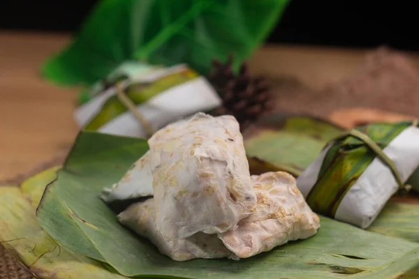 Tempe mentah: Muz yaprağı üzerinde çiğ tempeh (pişmemiş soya fasulyesi keki) .