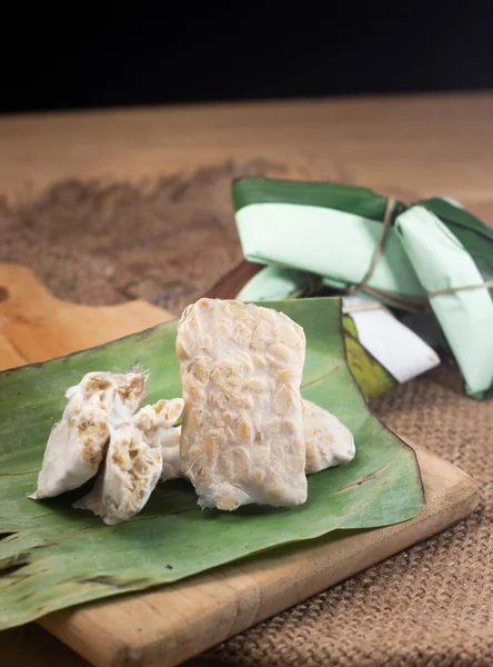 Tempe mentah: Muz yaprağı üzerinde çiğ tempeh (pişmemiş soya fasulyesi keki) .