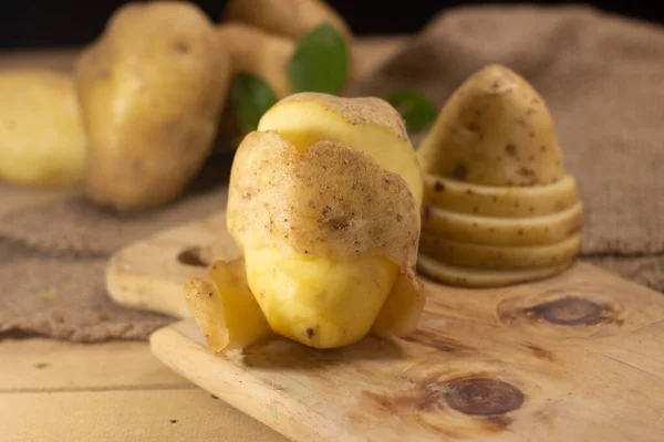 Raw potato with the twirling skin peel . Fresh potato on cutting board