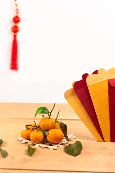 Çin Yeni Yıl Festivali dekorasyonu. Çin zarfı, portakal, yaprak, kırmızı paket, ahşap arka planda. (Zarftaki Metin Mutlu Yıllar ve Mutluluk anlamına gelir)