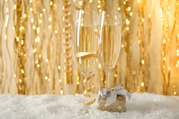 Champagne glasögon och gåva mot bakgrund med gyllene band — Stockfoto